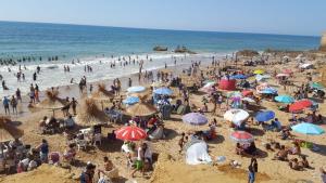 a crowd of people on a beach with umbrellas at Younes residence in Asilah