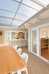 a dining room with a wooden table and white chairs at Lukes Kitchen Bach in Kuaotunu
