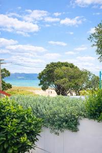 a white fence with a view of the beach at Lukes Kitchen Bach in Kuaotunu