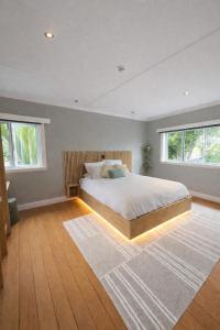 a bedroom with a bed with a wooden headboard and windows at Lukes Kitchen Bach in Kuaotunu