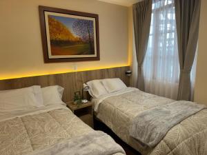 a hotel room with two beds and a picture on the wall at CASA ETEN Hospedaje Boutique - centro histórico de Cajamarca in Cajamarca