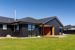 a house with a black roof and a yard at Style, Space and Comfort in Twizel