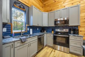 a kitchen with white cabinets and a stove top oven at New listing-- Hocking Hills Modern Cabin in Logan