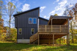a black house with a large deck on the grass at New listing-- Hocking Hills Modern Cabin in Logan