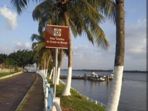 a sign next to a river with palm trees at Suíte Morada das Mangueiras Térreo in Soure