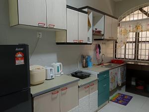 a kitchen with white cabinets and a black refrigerator at ROSSA Condo 1 in Kuah