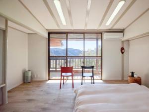 a bedroom with two chairs and a bed and a large window at Oyado S in Hakone