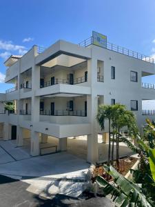 a large white building with palm trees in front of it at Villa resort -悠- in Miyakojima