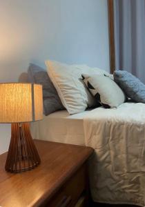 a bed with pillows and a table with a lamp at Estadia central bh in Belo Horizonte