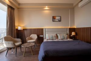 a hotel room with a bed and two chairs at The Sterling Omaxe Near Expo Mart in Greater Noida