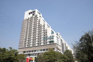 a tall white building with trees in front of it at The Sterling Omaxe Near Expo Mart in Greater Noida