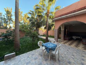 a table and chairs on a patio with palm trees at Airport agadir villa in Agadir