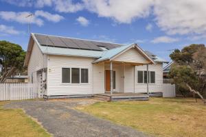 a white house with a solar roof at Surf Beach Remote Retreat in Surf Beach