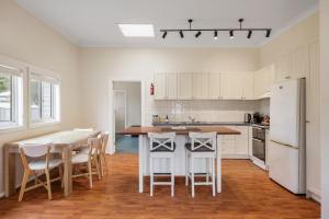 a kitchen with white cabinets and a table and chairs at Surf Beach Remote Retreat in Surf Beach