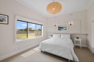 a white bedroom with a bed and a window at Surf Beach Remote Retreat in Surf Beach