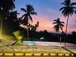 a pool with palm trees and a sunset in the background at Villa Indeewara in Welipenna East +6 photos