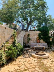 a stone patio with a bench and a tree at Beit Al Rahi in Ḑahr al Ḩarf