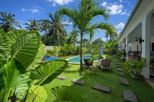 a backyard with a swimming pool and palm trees at Wanderlust Hostel - Highest Privacy Hostel In Kuta - Big Clear Pool - Fast Internet in Kuta Lombok