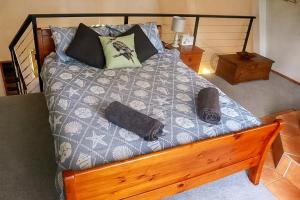 a bed with a wooden frame and pillows on it at LAKE VIEW CHALET Australia Zoo close by in Landsborough