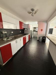 a kitchen with red and white cabinets and a black floor at Casa con piscina privada Girardot in Girardot