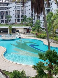 a large swimming pool with palm trees and buildings at ROSSA Condo 1 in Kuah