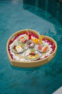 a tray of food on a table in a swimming pool at Villa Origami by Nagisa Bali in Seminyak