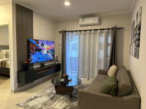 a living room with a couch and a flat screen tv at Moonlight Apartment in Gaborone