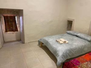 a bedroom with a bed with a pair of shoes on it at beit al moukhtar in Ḩārat at Taḩtā