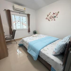 a bedroom with a bed with blue sheets and a window at Kitjamyhome2 in Ban Tha Thon