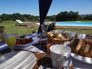 a picnic table with plates of food and a drink at La Rolandie Haute in Limeuil