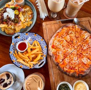 a table with plates of food and a pizza and french fries at Tropical Temple Siargao Resort in General Luna +41 photos