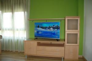 TV de pantalla plana en la parte superior de un centro de entretenimiento de madera en Apartamentos Costa Costa, en Suances