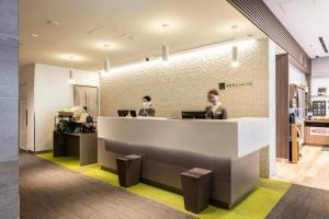 two people sitting at a counter in an office at KOKO HOTEL Hakata Shinkansenguchi in Fukuoka