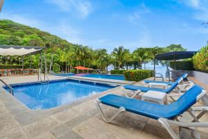 a swimming pool with two chairs and a table at Bahia Pez Vela Resort in Ocotal