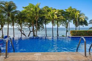 a swimming pool with palm trees and the ocean at Bahia Pez Vela Resort in Ocotal +233 photos