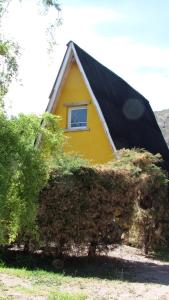 una casa amarilla con techo negro y ventana en Complejo de Cabañas Tierra de Luna en Potrerillos