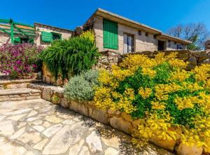 a stone retaining wall with flowers in front of a house at Holiday home Kuzmino in Primošten