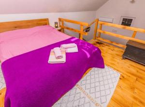 a bed with a purple blanket and two towels on it at Holiday home Kuzmino in Primošten