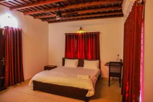 a bedroom with a bed and red curtains at Jotham Gardens in Alleppey