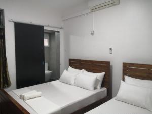 a bedroom with two beds with white pillows at Wicks Backpacker's Lodge - Peaceful Quality stay, Walk to the Historic Galle Dutch Fort and the beach in Galle