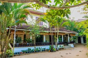 a house with palm trees in front of it at Jotham Gardens in Alleppey