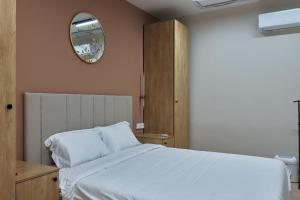 a bedroom with a white bed and a mirror at Kalion Capsule and Boutique Hotel in Almaty