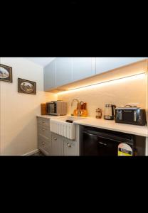 a kitchen with white cabinets and a black dishwasher at The old shearers quarters in Glentunnel +6 photos