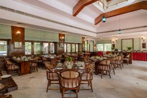 a dining room with tables and chairs and windows at juSTa The Bagh, Kanha in Bhīmlāt