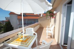 d'une table et de chaises sur un balcon avec un parasol dans l'établissement Apartments Novalja, à Novalja