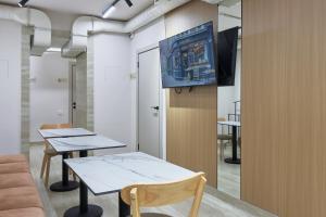 two tables in a room with a tv on the wall at Kalion Capsule and Boutique Hotel in Almaty