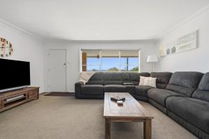 a living room with a couch and a tv at The Nelson Bay Getaway in Nelson Bay