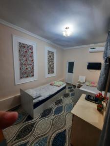 a small room with two beds and a table at Orzu Guest House in Bukhara