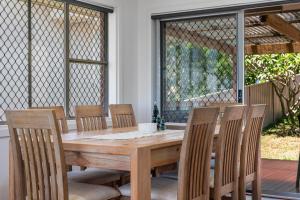 a wooden dining room table with chairs and windows at The Nelson Bay Getaway in Nelson Bay