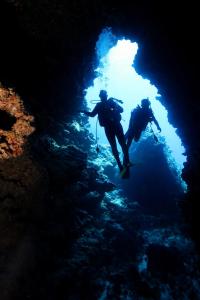 two people are diving into a dark cave at Flying Annie Moa in Neiafu